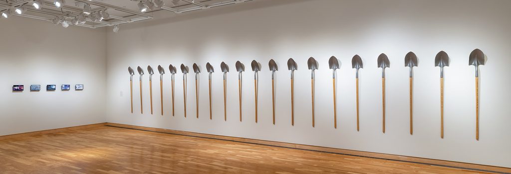 Twenty-one shovels made using melted down guns displayed on a wall in the Perlman Teaching Museum