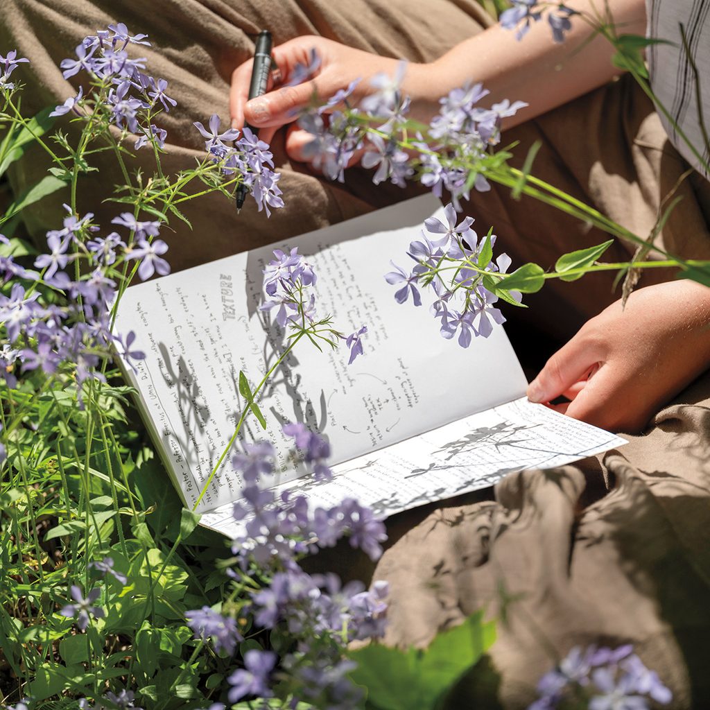 Ruby Dirks ’26 reviews her field notes journal while sitting in the arboretum