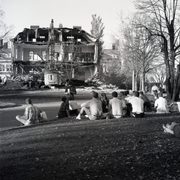 students sit on a hillside watching a building being torn down