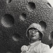 Hyper-realistic drawing of a black woman standing in front of a meteorite, holding wiffle balls