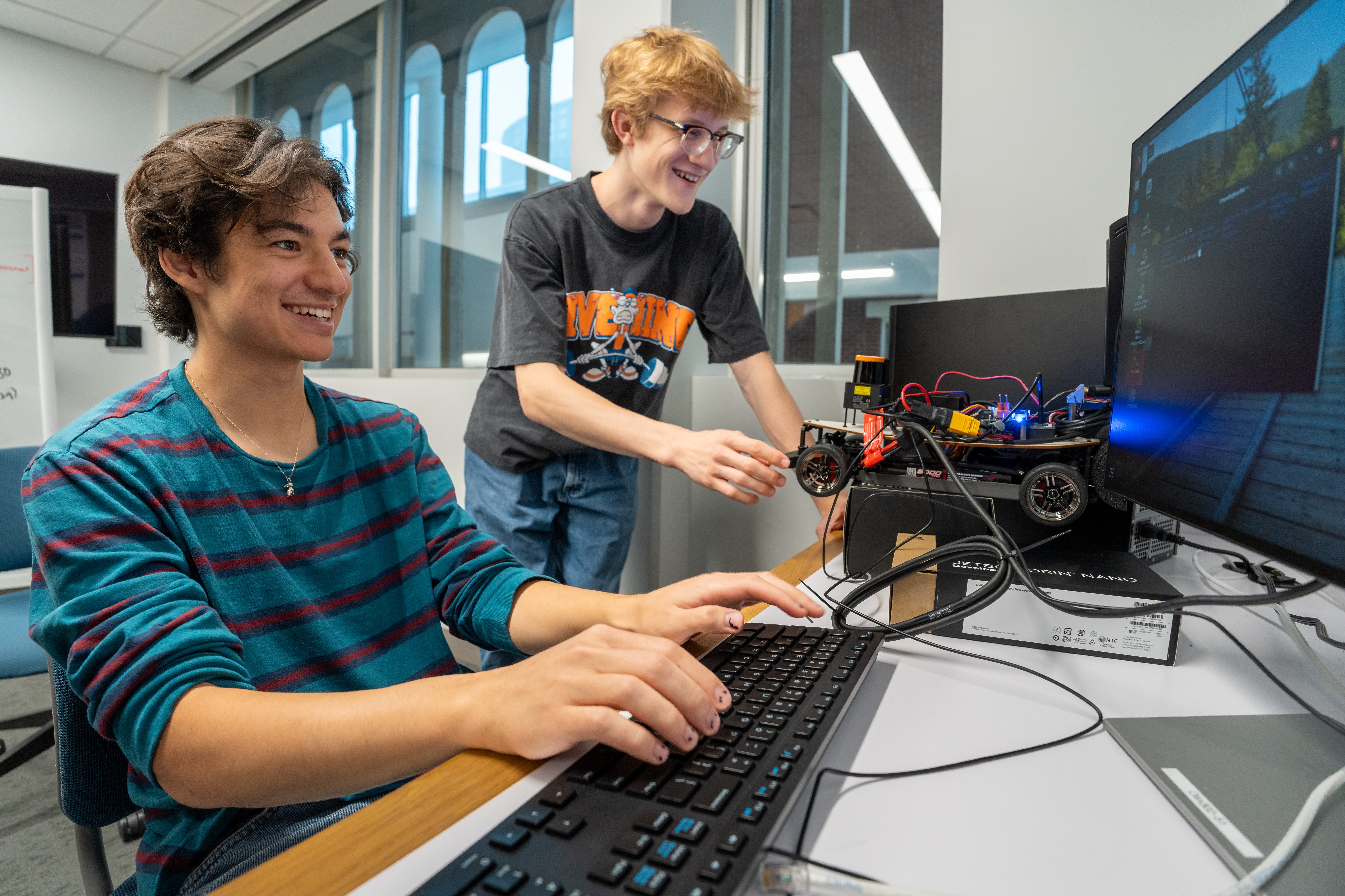students collaborate on a coding research project at a computer