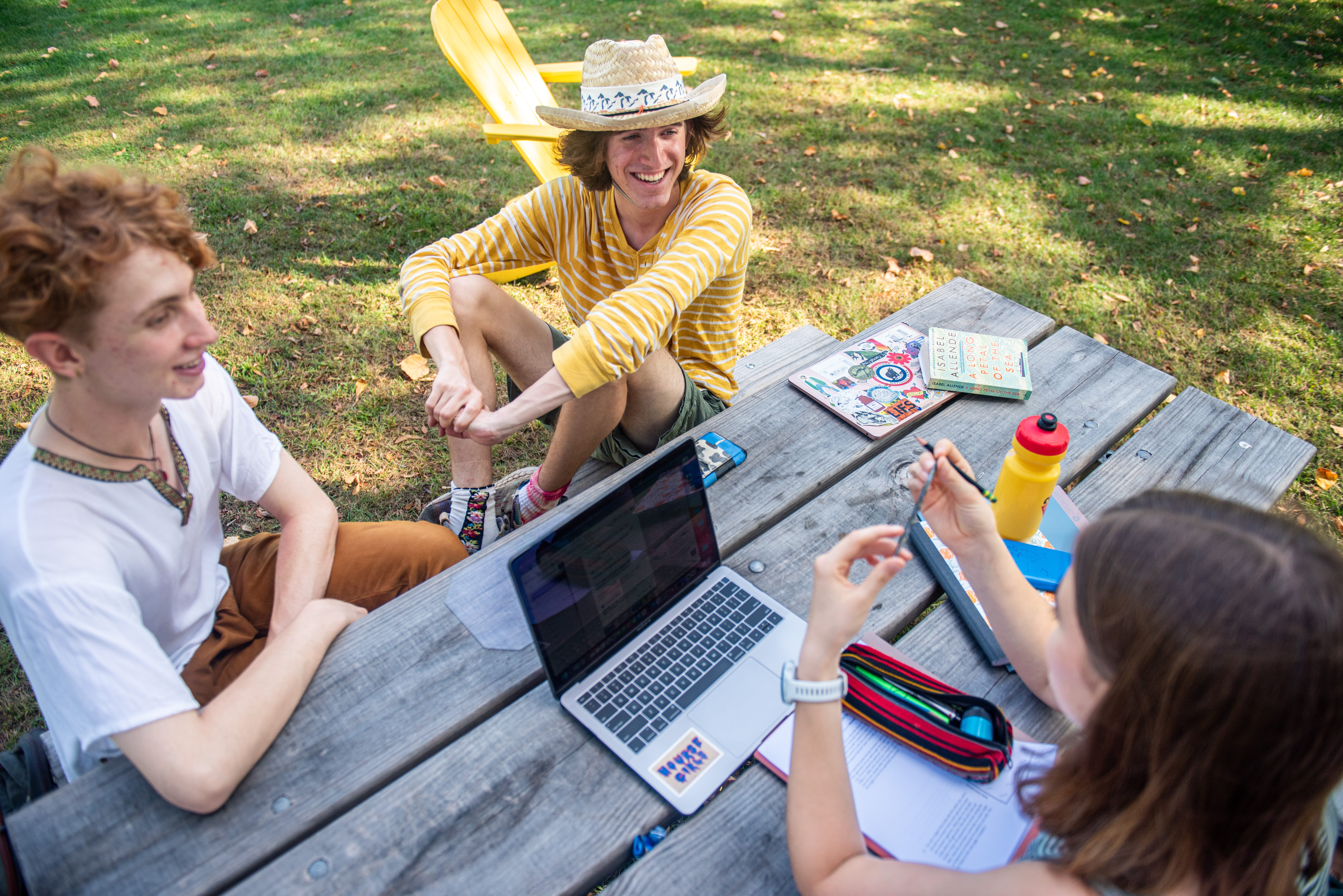students sit at a picnic table and have a conversation