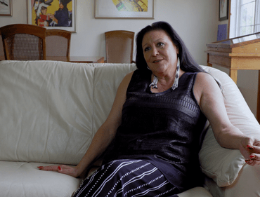 Ramona Kitto Stately sits on a couch looking as though she's listening or telling a story.