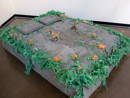 a bed made of cement-covered cardboard decorated with plastic vegetation
