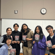 A group of student editors stand in a row, showing off their work, 
