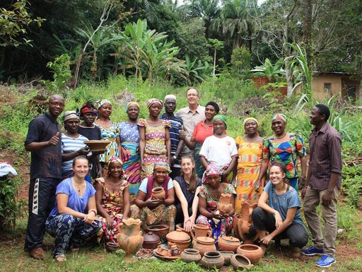 Students and community members pose for a picture with traditional pottery