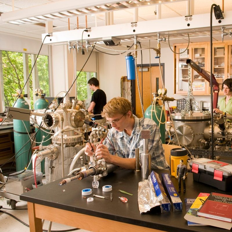 Two students and a professor work in a campus physics lab