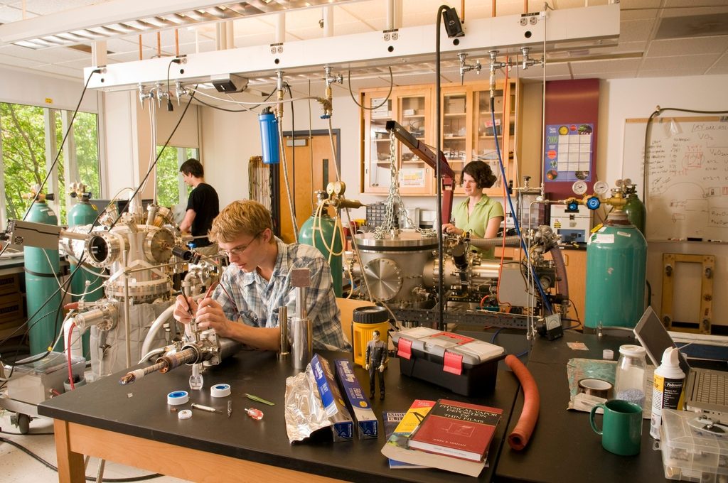 Two students and a professor work in a campus physics lab