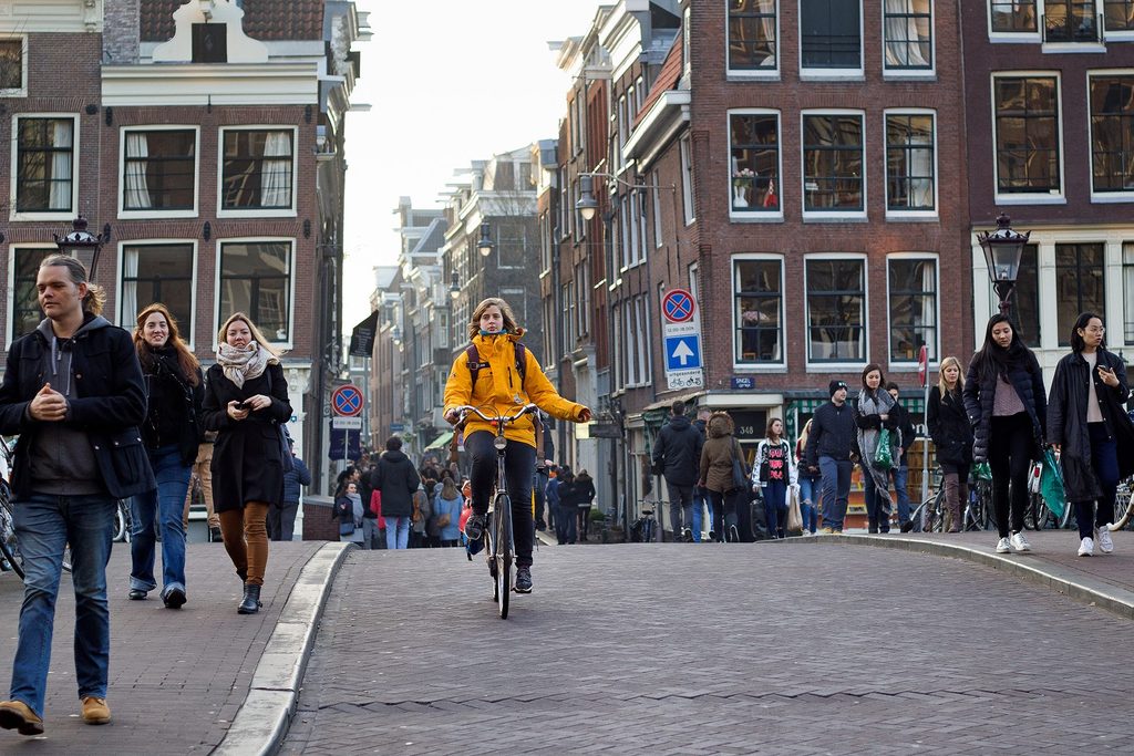 A woman rides a bike through a hilly street in Amsterdam