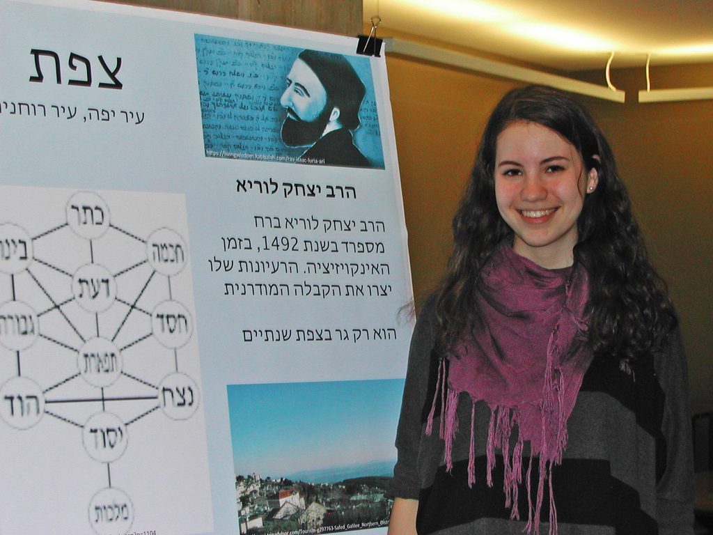 Evie Rosenberg '17 stands beside a poster in Hebrew