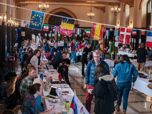 Students and professors at the Off Campus Studies World's Fair, with banners showing the flags of many nations