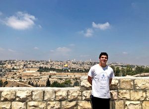 Aaron Forman stands against a stone wall overlooking Jerusalem