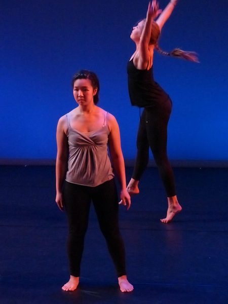A dancer standing still in the front and another dancer moving behind her