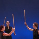 Three dancers holding up sticks