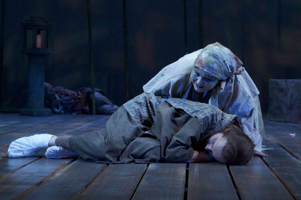 A woman hovering over a sleeping man