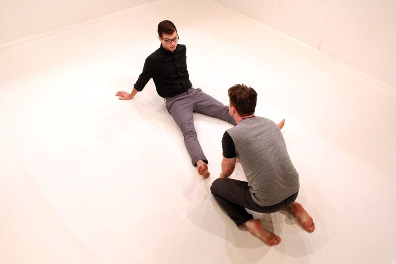 Two men seated on a white floor