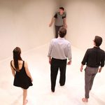 Man being cornered in an empty white room by three other actors