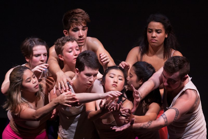 Dancers huddled together and reaching forward