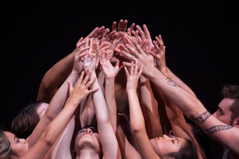 Dancers reaching their arms up together