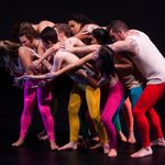 Dancers wearing colorful pants huddled together
