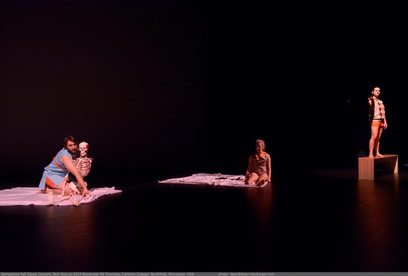 Two dancers sitting on blankets and another dancer standing behind on a bench
