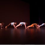 Dancers doing a high plank position in a line