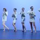 Dancers in white dresses standing in front of a blue background