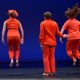 Three dancers in orange facing the back of the stage