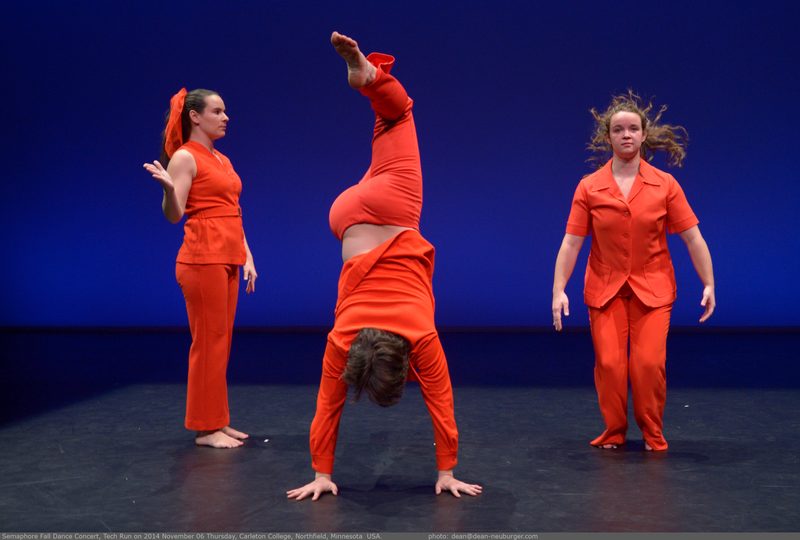 A dancer doing a hand stand and two other dancers standing