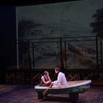 A man and a woman in a row boat on stage