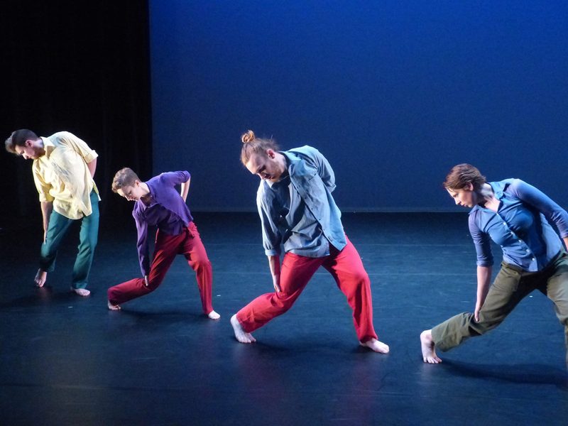 Four dancers with knees bent, looking at the floor