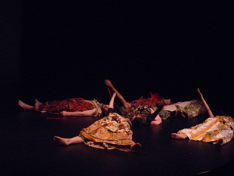 Dancers wearing dresses and laying on the floor