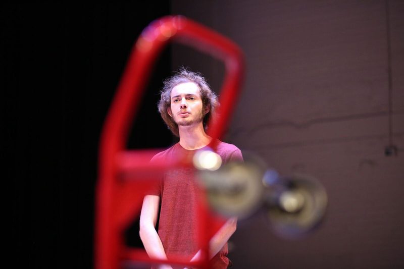 Man in a red shirt standing behind an unfocused red dolly