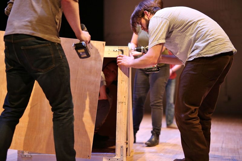 Men using drills to assemble a large wooden box