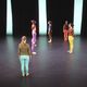 Dancers wearing bright colors standing on stage.
