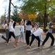 Company members practice a piece outside on a sunny fall day. They are barefoot and striking poses.