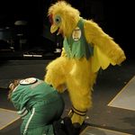 A person in a chicken costume standing over a person wearing a race car outfit