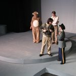 Actors standing on stage, one wearing a bear costume