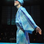 A man wearing a robe and a hat with eyes under blue lights