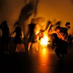 A blurry image of dancers dancing around a light