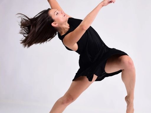 White background, a dancer in black outfit arms and legs extended