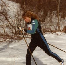 Brigette skiing through a course, wearing a uniform with teal accents