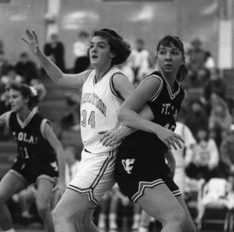 Shallenberger blocks a St. Olaf defensive player, arm outstretched for the basketball