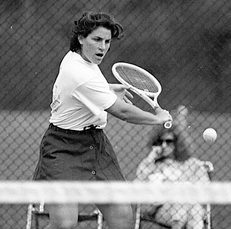 Gale swings her tennis racquet back, preparing to hit the ball back over the net