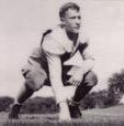 Johnson kneels, one hand on the field, the other propped on his knee