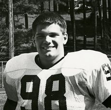 Ethen, #98, poses smiling for the camera on the Carleton College football field