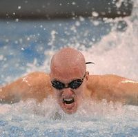 Marschall swims butterfly wearing a light pink swim cap