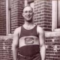Rolfe stands in front of a building in uniform, smiling widely