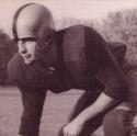 Machacek kneels, ready to run, in his football uniform