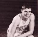 Slocum kneels, one hand on a basketball